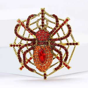 Spider web brooch with vintage gold finish and red rhinestones on white background