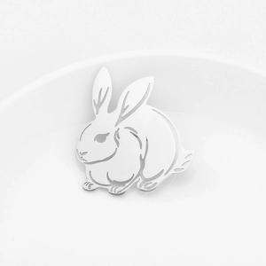 Vue détaillée d'une broche lapin en argent avec gravures ajourées sur une assiette blanche