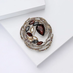 Detailed close-up of a vintage bird nest brooch with red crystals and silver metal