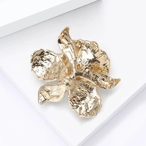 Detail der eleganten goldenen Orchideenbrosche mit Blütenblattstruktur auf weißem Stand