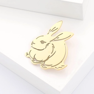 Détail d'une broche lapin dorée en acier inoxydable avec un design ajouré élégant sur bloc