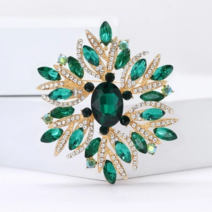 Macro shot of gold alloy flower brooch featuring green crystals and white rhinestones
