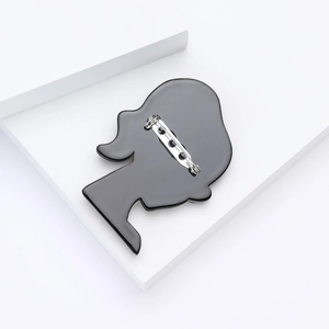 Close-up of a glossy black acrylic girl silhouette brooch with a secure metal pin back
