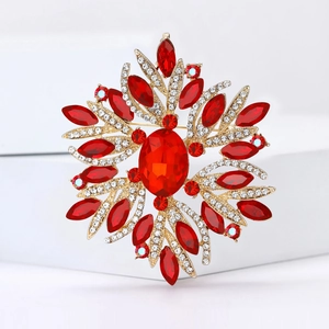 Macro view of a radial flower brooch with red crystal gems on a gold alloy base