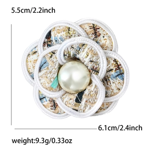 Detail of camellia flower brooch with colorful woven fabric and central faux pearl