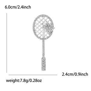 Detailed view of silver tennis racket brooch with sparkling rhinestones and white pearl