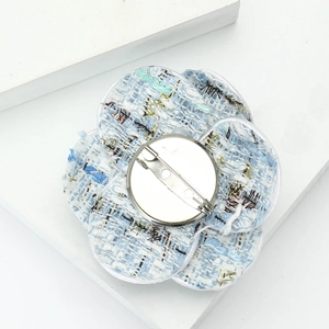 Macro detail of camellia fabric brooch in blue and white tweed with silver pin