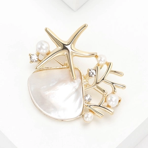 Elegant gold starfish and seashell brooch with pearls and rhinestones on white background