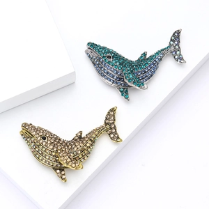 Creative whale brooch set with blue-green and gold crystals on a geometric stand
