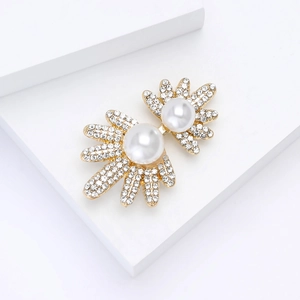 Détail de la broche feuille avec perles blanches et strass sur base dorée élégante