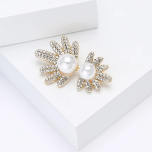 Vue détaillée d'une broche feuille dorée avec perles blanches et strass scintillants