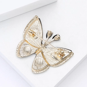 Vue détaillée du dos de la broche papillon dorée montrant le fermoir et la texture métal