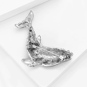 Detailed back view of silver whale brooch with secure rotating pin and textured finish