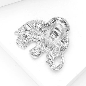 Macro detail of elephant brooch back showing silver metal texture and safety pin clasp