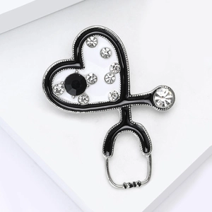 Détail de la broche stéthoscope cœur avec strass et émail noir sur support blanc