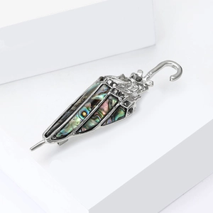 Silver umbrella brooch with colorful abalone shell inlay on minimalist white background