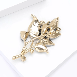 Détail du dos de la broche fleur en métal doré montrant l'épingle de fixation sûre