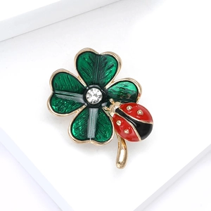 Detailed close-up of a golden ladybug and green four-leaf clover brooch with a crystal
