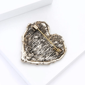 Detail view of heart brooch back showing vintage alloy texture and secure pin closure