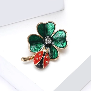 Close-up of enamel ladybug and green clover brooch with sparkling crystal center