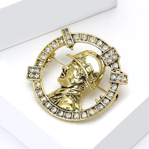 Detailed close-up of a vintage gold-toned lapel pin with rhinestones and figure relief