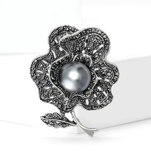 Elegant vintage flower brooch with grey pearl and dark crystals on a white display pedestal