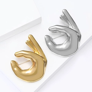 Broches main OK minimalistes en émail doré et argenté sur socles géométriques blancs