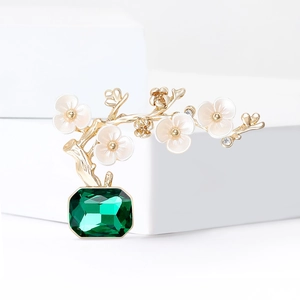 Elegant plum blossom bonsai brooch with green gemstone and gold branches on white cubes