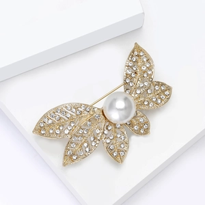 Détails d'une broche en forme de feuille avec strass brillants et perle centrale