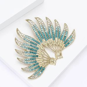 Macro shot of elegant gold brooch with blue gradient rhinestones in wing design