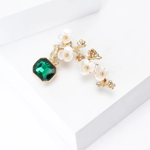 Detail view of flower plum blossom brooch with emerald stone and gold branch