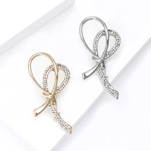 Elegant gold and silver knot brooches with pavé rhinestones on a white geometric background