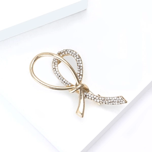 Detailed view of elegant gold-toned knot brooch with sparkling rhinestones and ribbon design