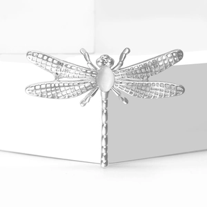 Silver hollow dragonfly brooch with opal gemstone on a white minimalist pedestal