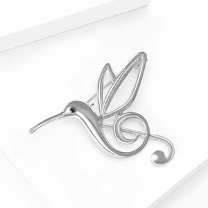 Detailed macro view of silver hummingbird brooch with treble clef design and black gem eye