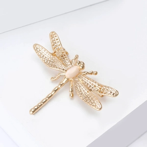 Macro detail of golden dragonfly brooch with hollow wings and creamy opal stone