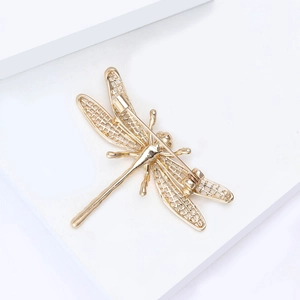Detailed back view of golden alloy dragonfly brooch with hollow wings and safety pin clasp