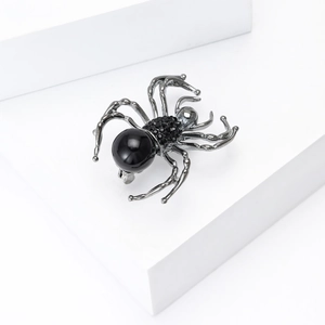 Macro shot of a gothic spider brooch with black pearls and rhinestones on white steps