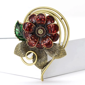 Vintage red flower brooch with gold leaves and green enamel on a clean display stand