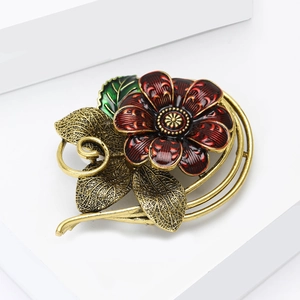Vintage enamel red flower brooch with antique gold leaves on white geometric stand