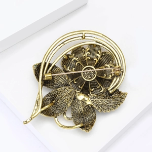 Close-up of vintage gold flower brooch showing detailed brushed texture and rear safety pin