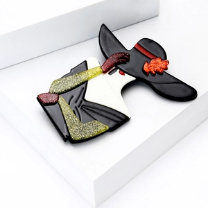 Detail of elegant Marilyn-style acrylic brooch with glitter accents on white podium