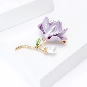 Close-up of lavender enamel magnolia brooch with golden stem and teardrop pearl detail