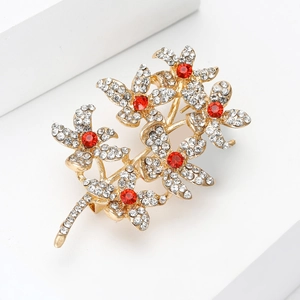 Close-up of golden flower brooch featuring sparkling rhinestones and red crystal centers