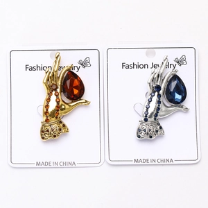 Detail of vintage hand-shaped brooches with colorful teardrop gemstones on a card