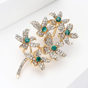 Detailed view of branch flower brooch with white crystals and emerald green stone