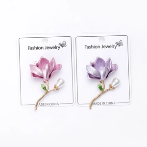 Detail showing pink and purple enamel magnolia brooches with pearls on gold-toned pins