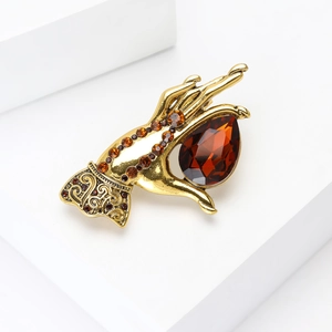 Detail of vintage hand-shaped gold brooch holding a pear-cut amber gemstone