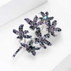 Close-up of elegant floral brooch with purple and blue crystals on white geometric surface