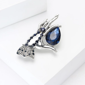 Detailed view of silver hand brooch with a large blue pear-cut gemstone and crystals